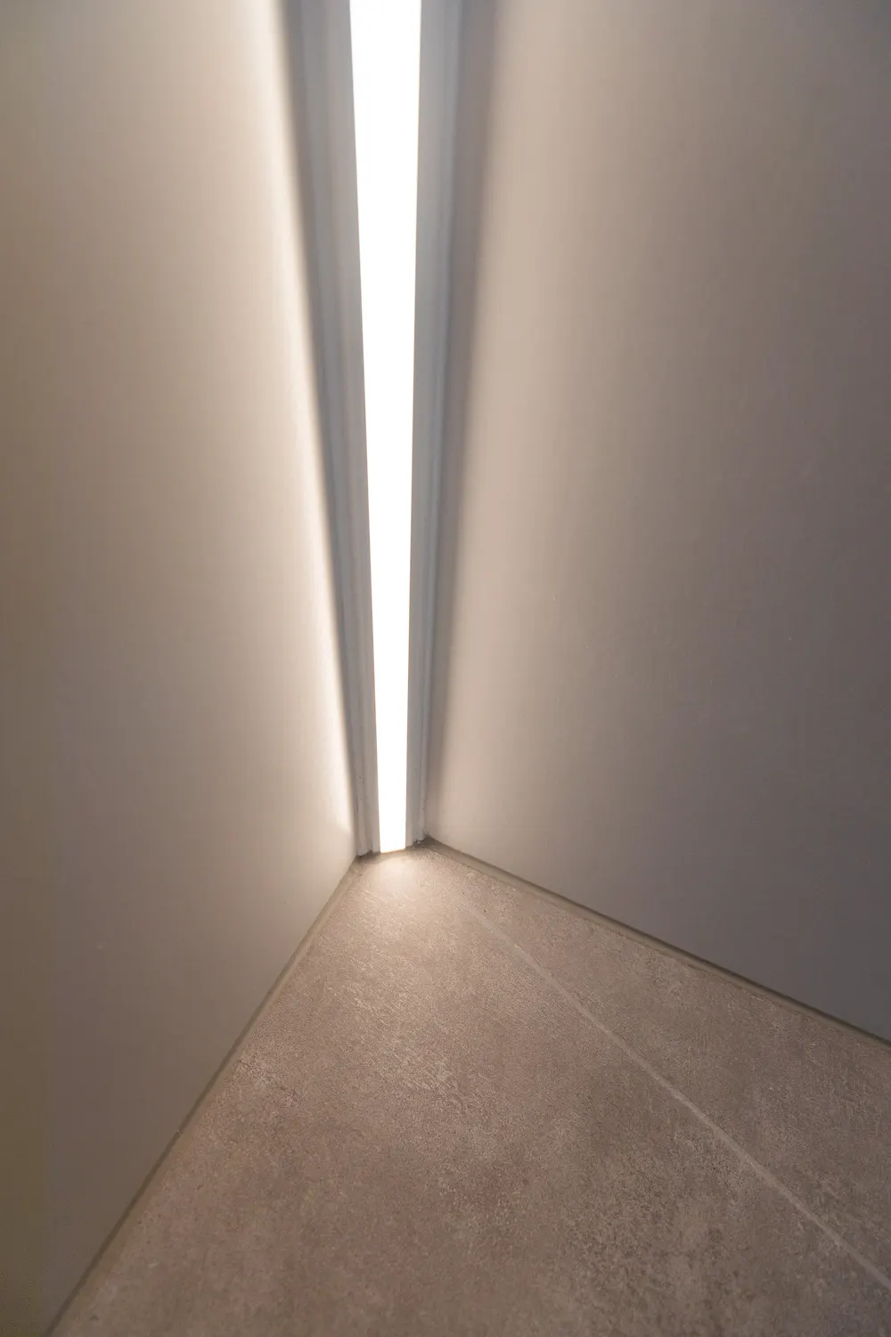 Großformatige Bodenfliesen in Grau mit Lichtleiste an der Wand